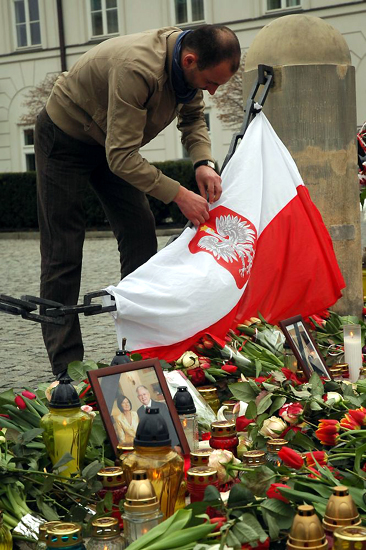 Mężczyzna przywiązuje flagę Polski pod Pałacem Prezydenckim